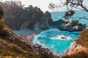 body of water near trees and mountain cliff during daytime