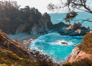 body of water near trees and mountain cliff during daytime