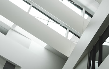 A modern interior with angular architecture, characterized by multiple levels and large windows. The design emphasizes clean lines and a minimalistic aesthetic.