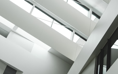 A modern interior with angular architecture, characterized by multiple levels and large windows. The design emphasizes clean lines and a minimalistic aesthetic.