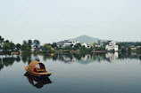 A traditional boat bobbing quietly on the misty lake surrounded by lush greenery.