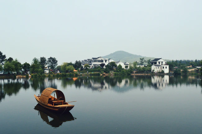 A traditional boat bobbing quietly on the misty lake surrounded by lush greenery.