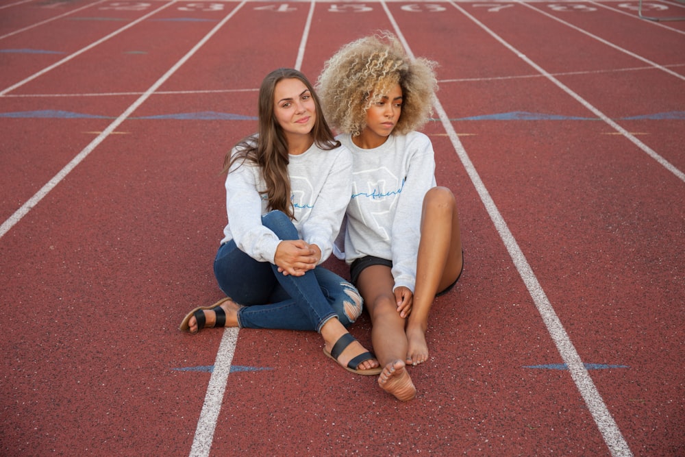 photograph of two woman seating on track field