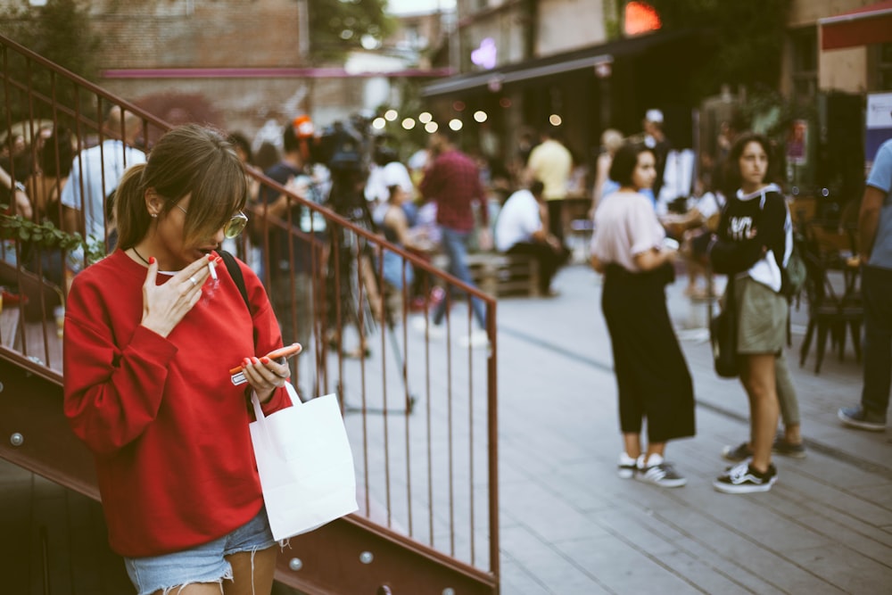 woman holding her smartphone outdoor during daytime