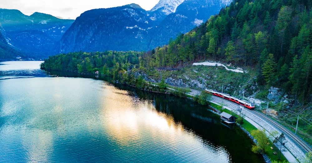a train traveling along a river surrounded by mountains
