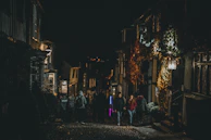 A cobblestone street at dusk with warm lights glowing from quaint shops.