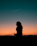 silhouette of woman standing under blue sky during golden hour