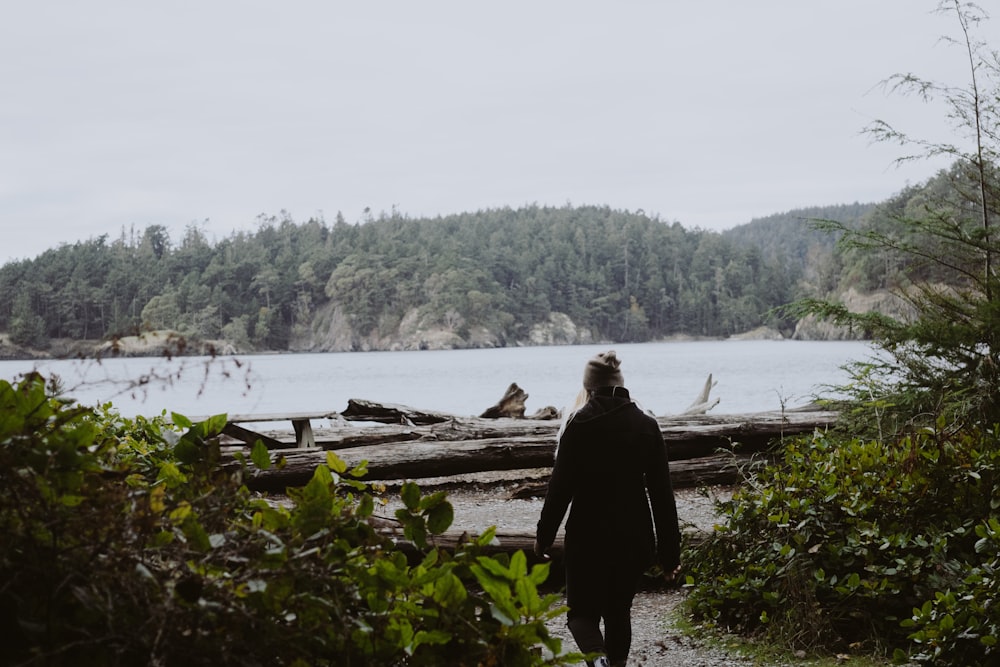 woman standing near the green plant and log during daytime