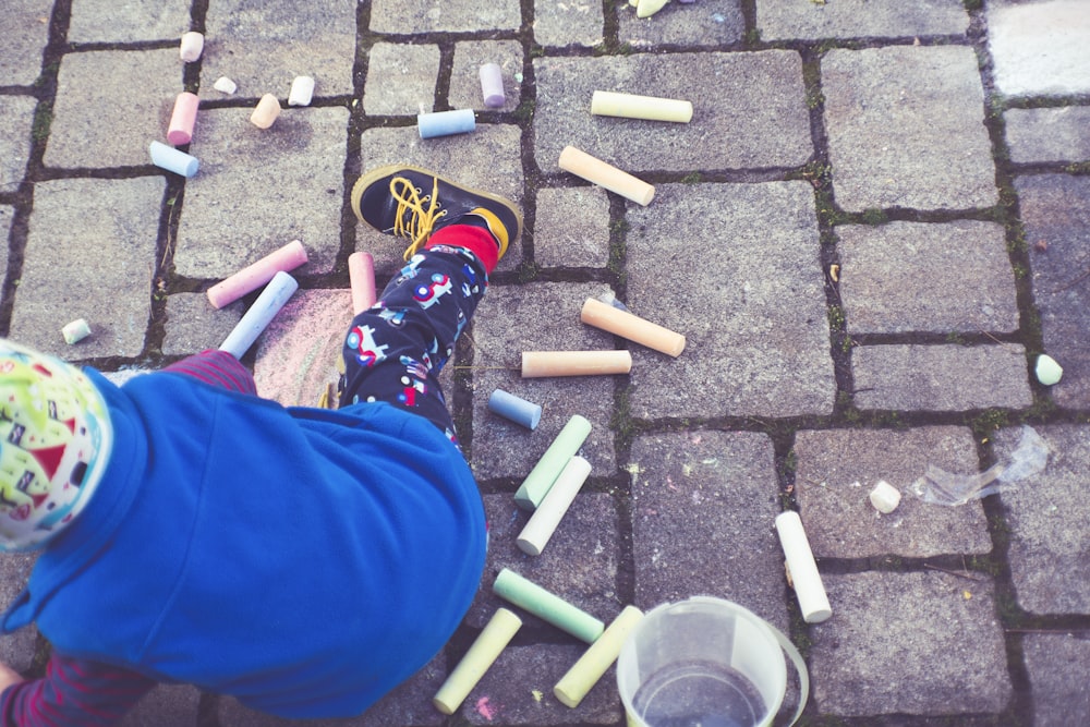 a child is playing with crayons on the ground