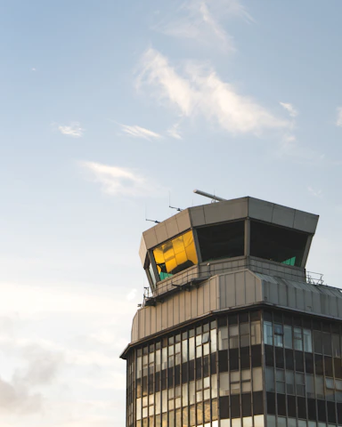 An air traffic control tower standing tall with a vibrant sunset backdrop.