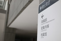 A sign in a modern building displays text in both English and Chinese. It provides directions to the Acquisition & Cataloguing Department, Compact Stacks, and Archives. The setting appears to be a university or a similar institutional environment with a sleek, minimalistic design.