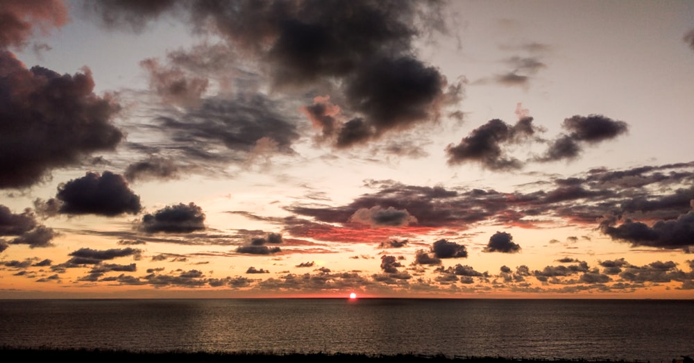 panoramic photo of sea water and clouds during golden hour