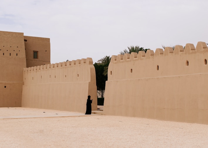 person wearing black clothes near beige wall during daytime