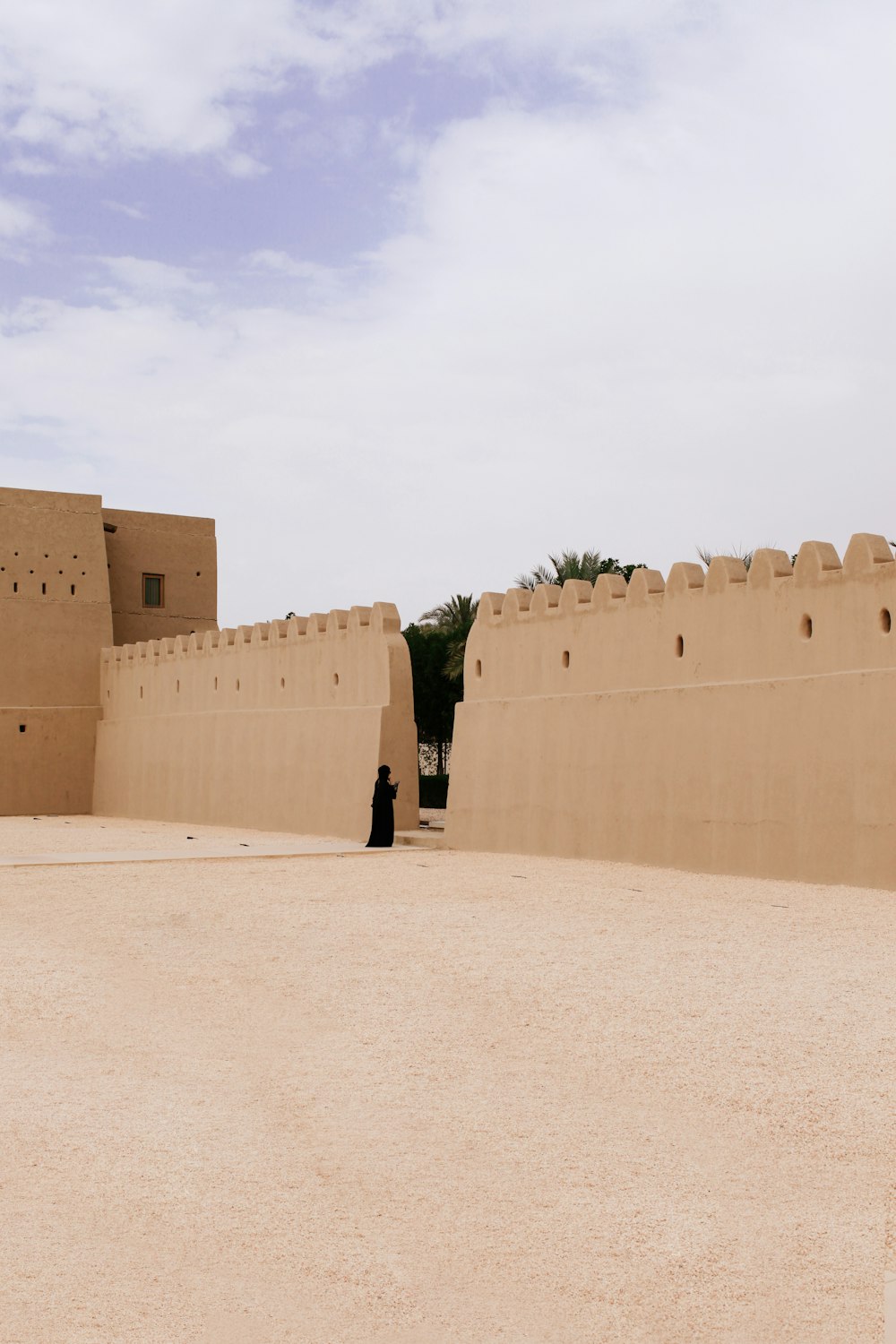 persona che indossa abiti neri vicino al muro beige durante il giorno