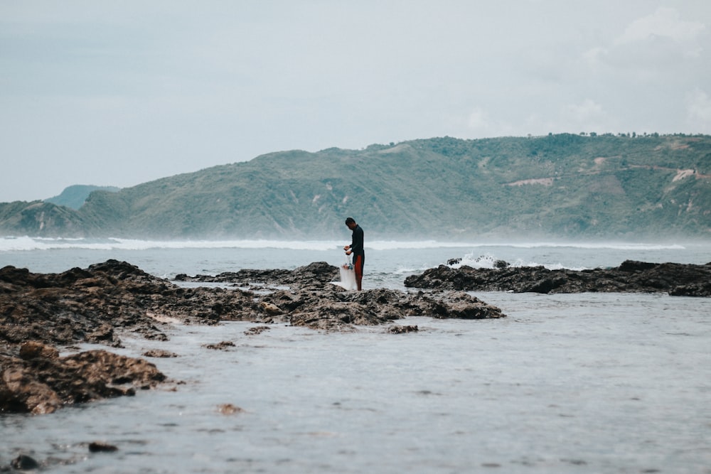 man standing on rocky seashore during daytime