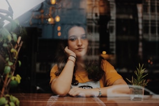 Thoughtful woman in close-up, with a potted plant, embodying the personal growth and homesickness 