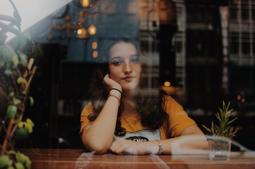 woman sitting next to table with hands on cheek