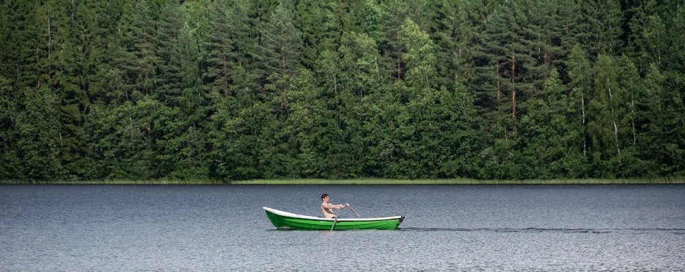 woman in blue shirt riding on green boat on river during daytime