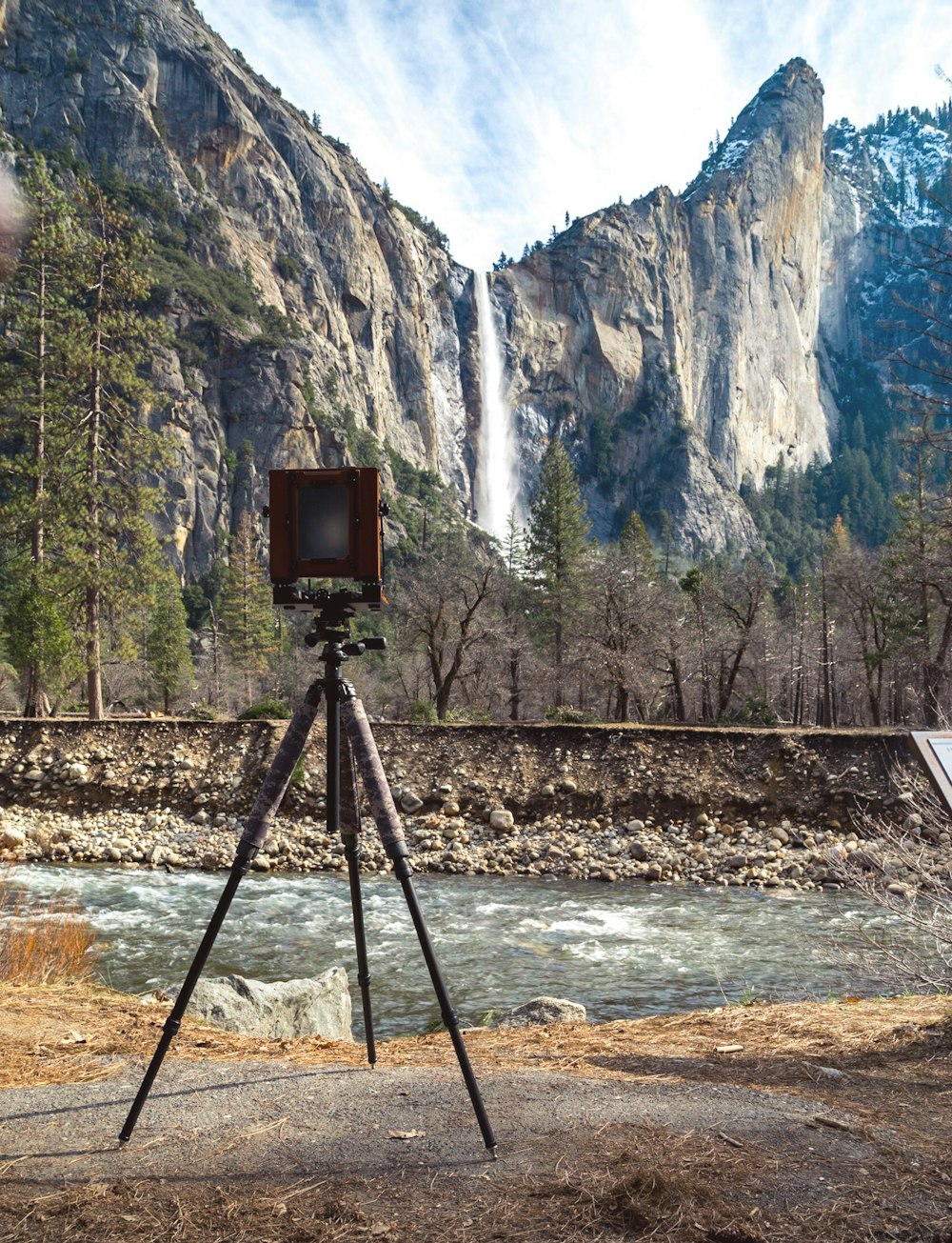 brown camera with tripod near on body of water