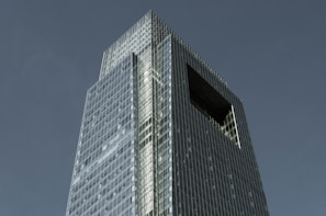 A sleek navy blue-toned skyscraper piercing a clear sky, symbolizing premium US real estate opportunities