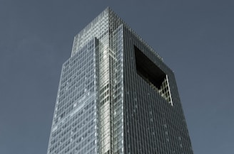 A sleek navy blue-toned skyscraper piercing a clear sky, symbolizing premium US real estate opportunities