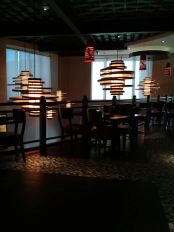 Wide shot of the interior showing warm brown tones, deep reds, and glowing pendant lights.