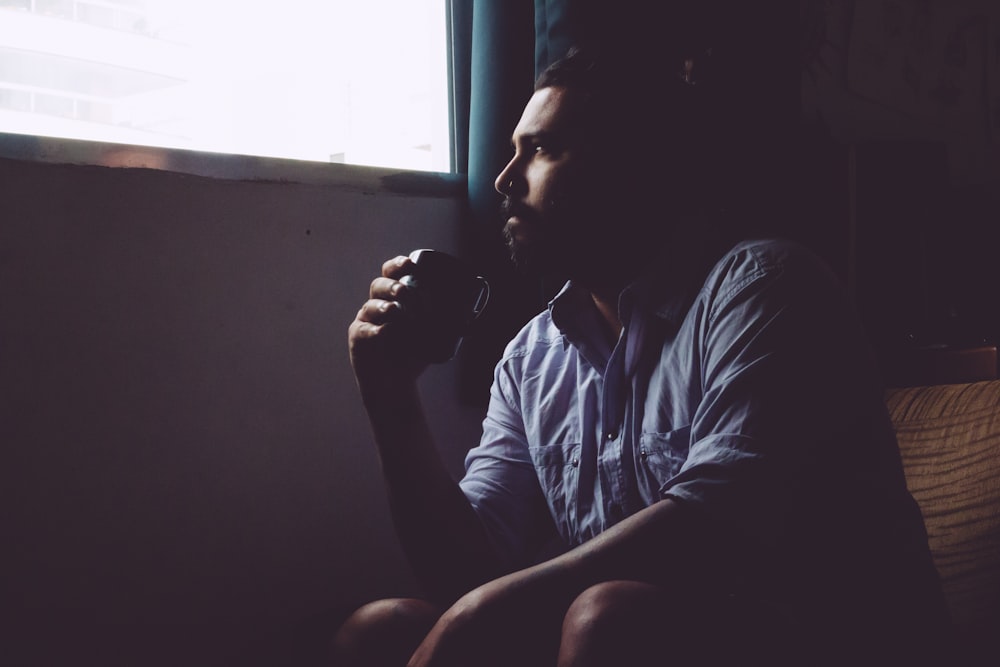 man sitting on chair holding mug