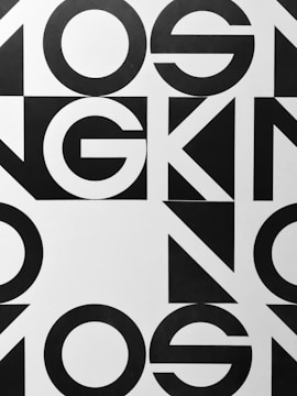 Bold black and white geometric typography with large, overlapping letters and shapes, creating an abstract pattern.