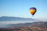 A colorful hot air balloon soaring gently over snow-capped alpine peaks at sunrise.