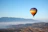 A colorful hot air balloon soaring gently over snow-capped alpine peaks at sunrise.
