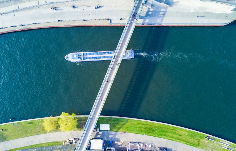 aerial photography of white boat passing under white bridge
