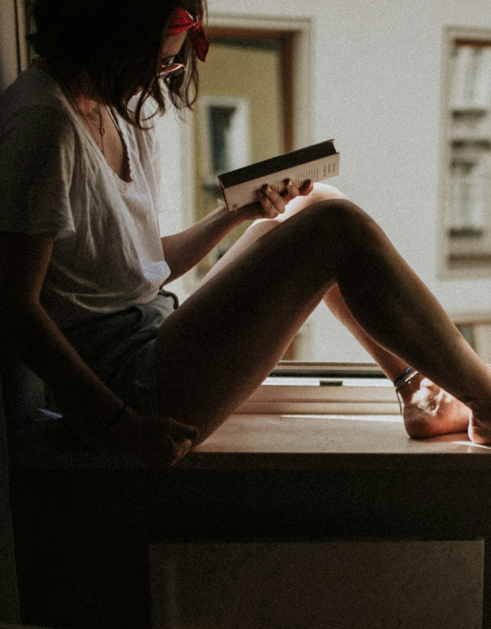 woman sitting on window holding book