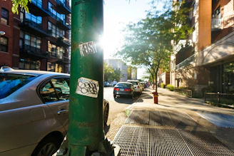A vibrant city street with cars featuring colorful Mobiluz branded stickers reflecting sunlight.
