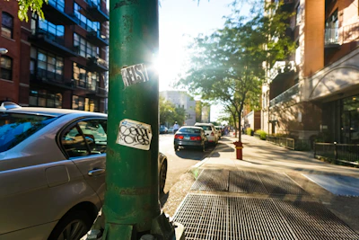 A vibrant city street with cars featuring colorful Mobiluz branded stickers reflecting sunlight.