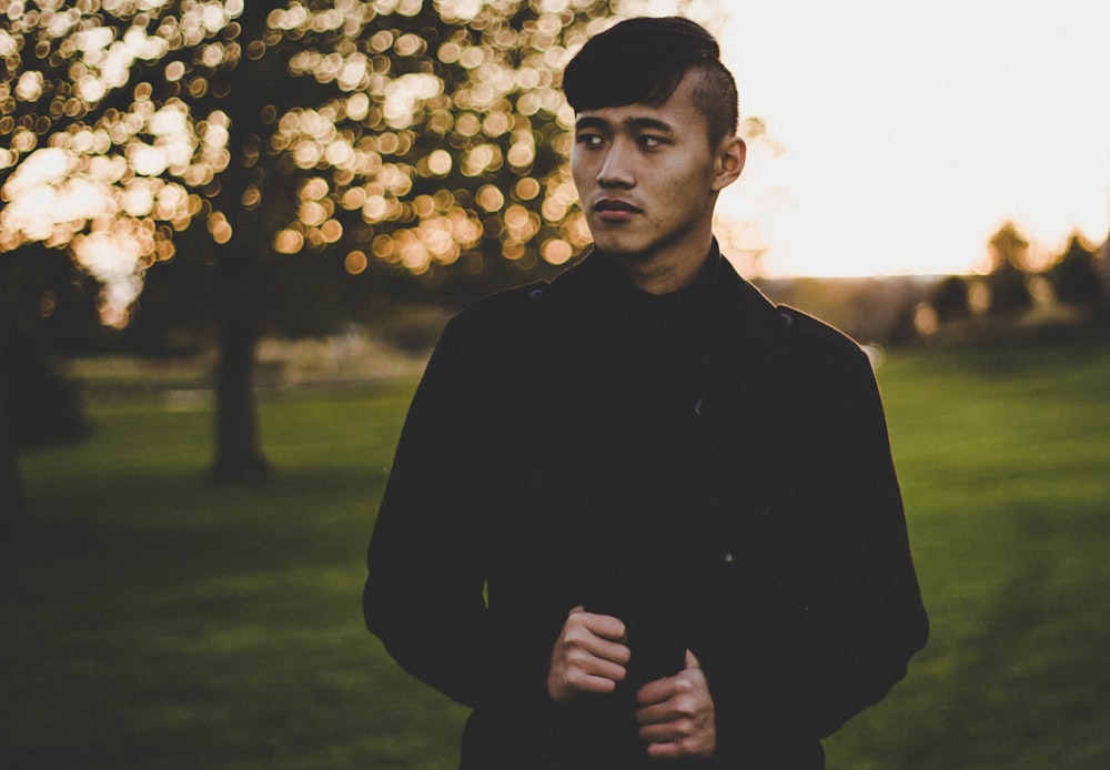 man standing on grass field near tree