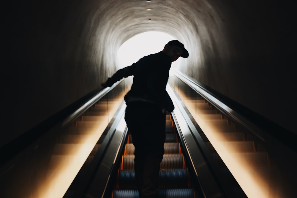 silhouette photo of man standing on escalator
