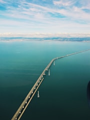 A sweeping aerial shot of a massive bridge construction site under a clear blue sky