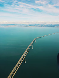 A panoramic view of a newly engineered bridge stretching across Puget Sound under a clear blue sky.
