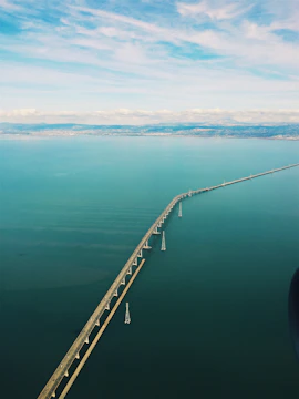 A panoramic view of a newly engineered bridge stretching across Puget Sound under a clear blue sky.
