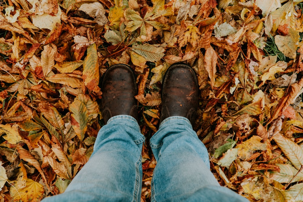 focus photography of man in leather boots standing on the leaves
