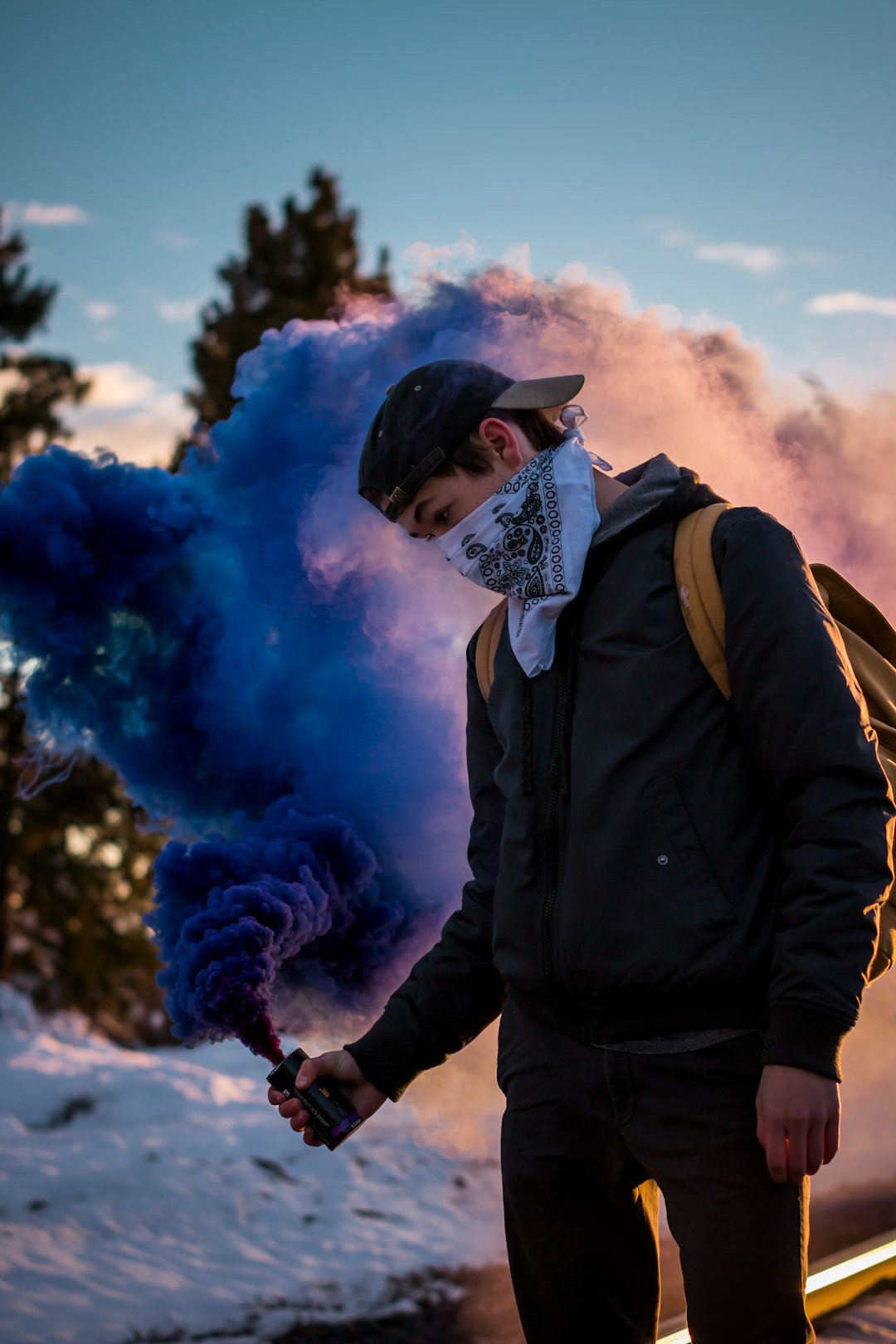 man wearing bandana holding blue smoke can standing