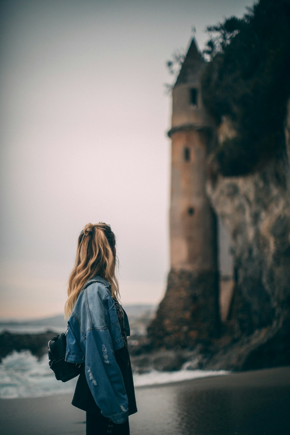 Photographie sélective de mise au point d’une femme sur le bord de mer près d’un phare