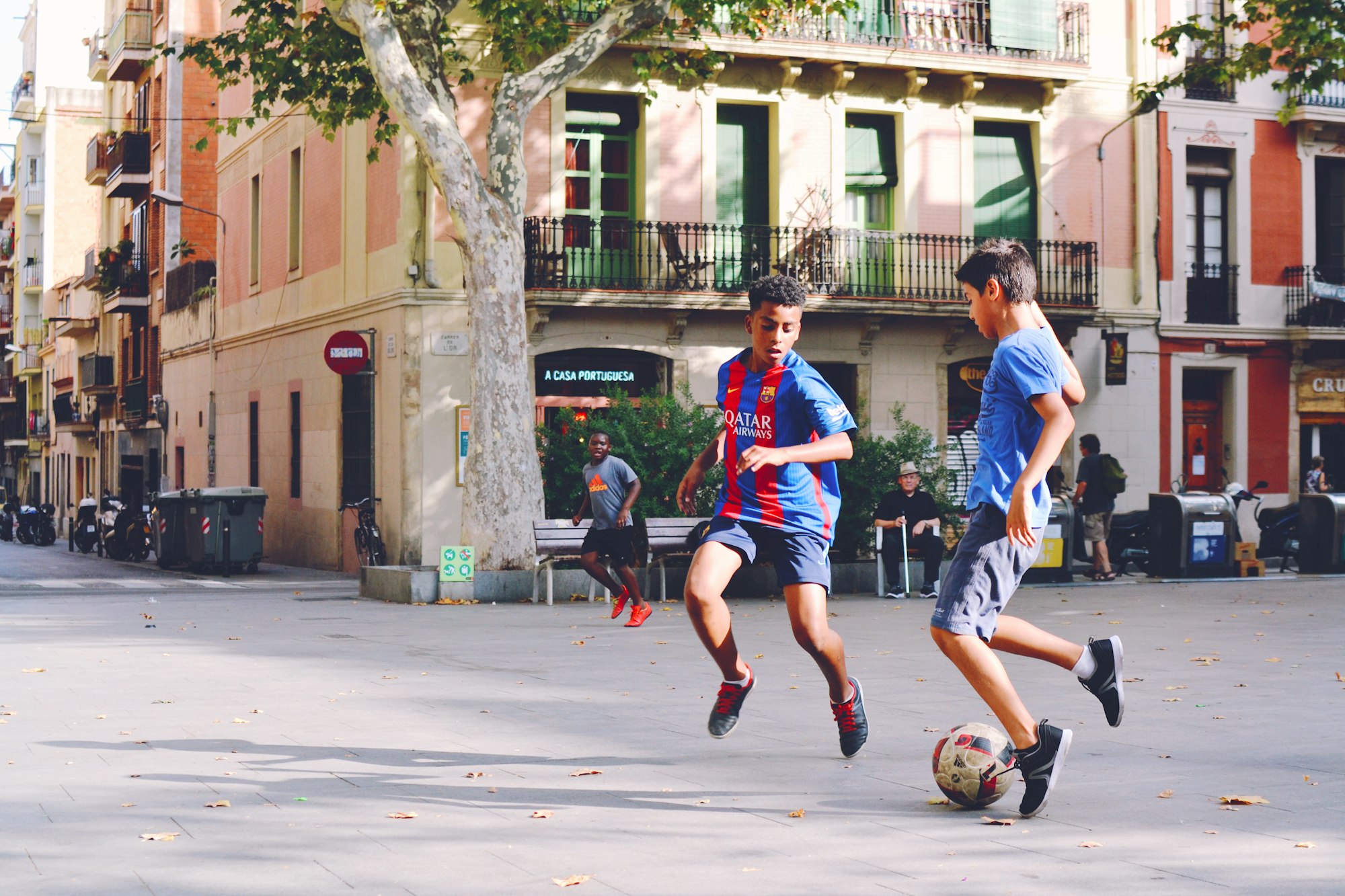 two boy's playing soccer near building during daytime