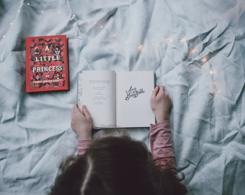 toddler holding book on bed