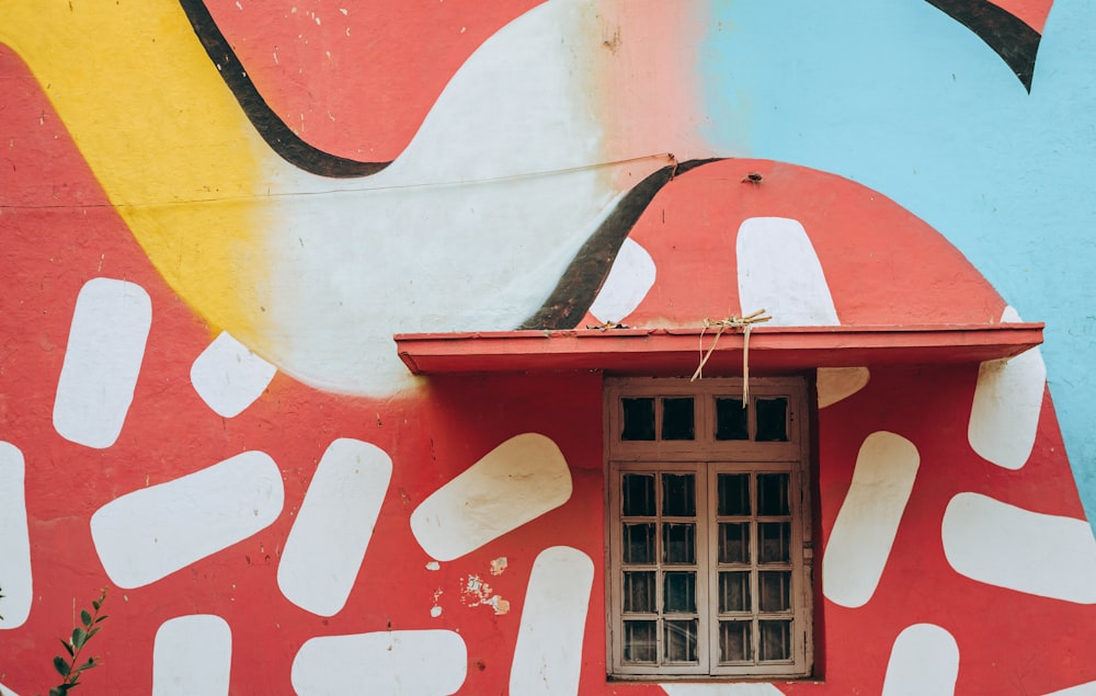 Ventana de madera blanca y mural rojo y azul