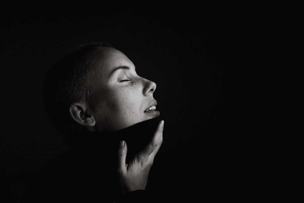 woman with hand on chin gray scale photography