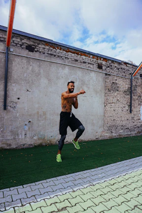Dynamic shot of a man wearing workout gear mid-jump against a graffiti wall.