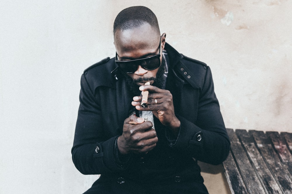 man in black coat holding brown tobacco