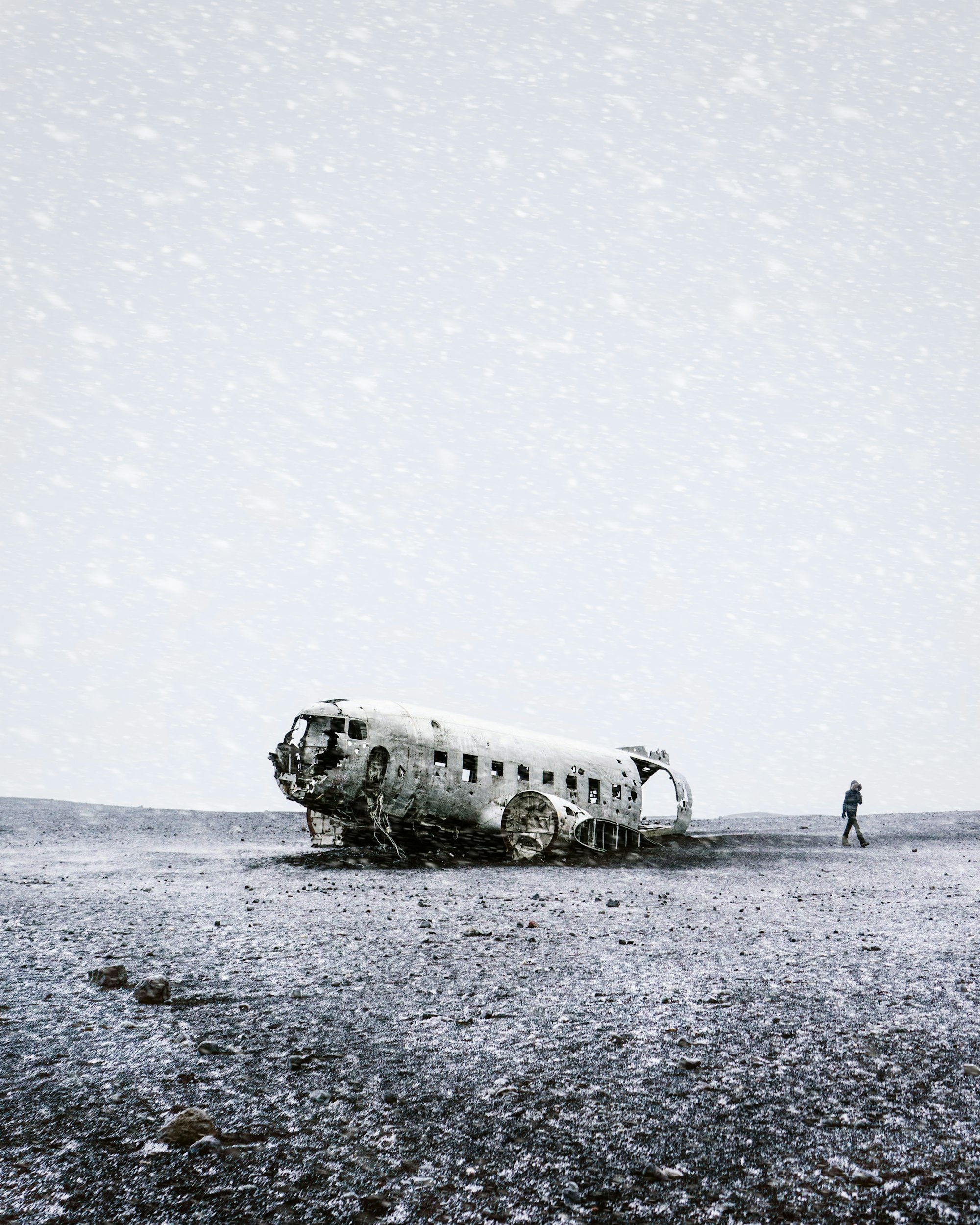 After walking for 45 minutes through horizontal snow and driving wind, we finally saw the shape appear of the whiteness. In this alien and martian landscape there is now color, simply the black sand of the beach and the white of the snow.