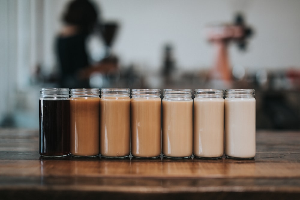 seven mason jars of coffee on table